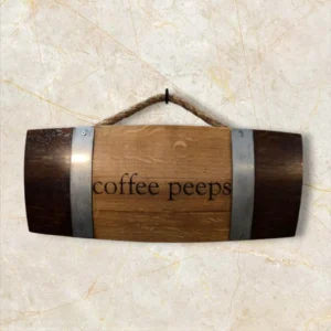 Rustic wooden wall sign made from a barrel stave with metal bands, engraved with "coffee peeps," and hung by a thick rope.